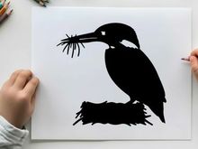 Silhouette of a kingfisher bird with twigs in its beak profile view