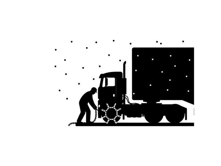 Silhouette of a man refueling a large truck on a snowy night