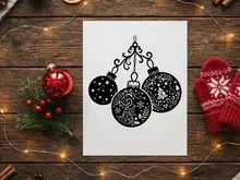 Black and white Christmas bauble ornaments hanging on a decorative scroll flourish.
