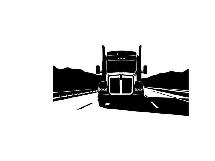 Silhouette of a semi truck driving on a highway with mountains