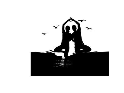 Silhouette of two people doing yoga on the beach at sunset
