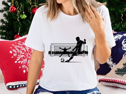 Soccer player kicking ball with goalkeeper attempting to block in a match