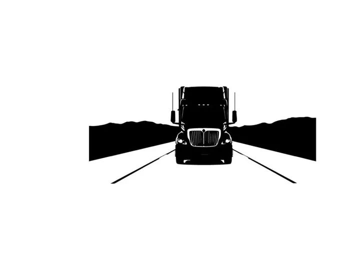 Truck silhouette on a road with mountains in the background silhouette