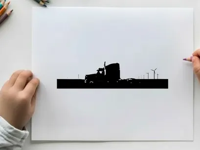 Silhouette of a semi truck driving on a road with wind turbines