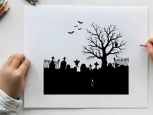 Spooky silhouette of a graveyard with a bare tree and flying birds