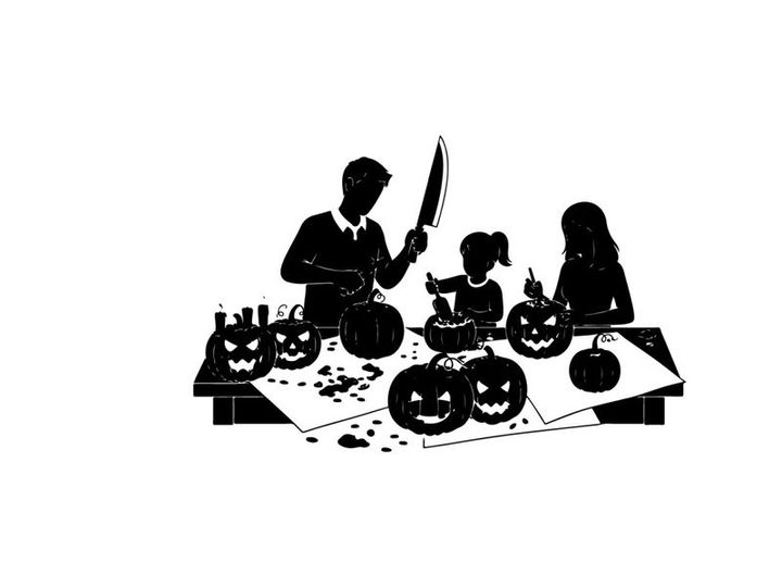 Family carving jack o lanterns in silhouette on halloween night