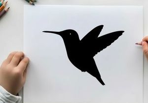Silhouette of a hummingbird in flight against a white background