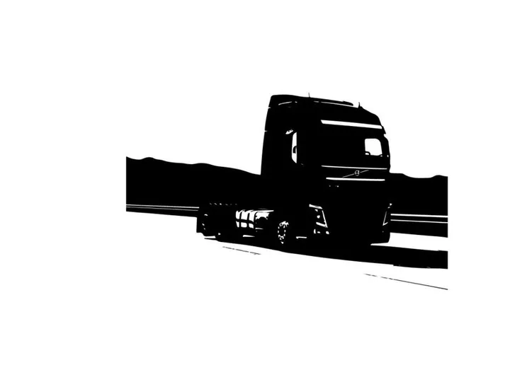 Silhouette of a large truck driving on a road
