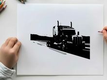 Silhouette of a semi truck driving on a highway with mountains