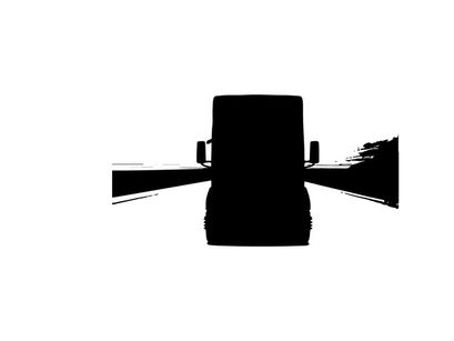 Silhouette of a large truck driving down a desert highway