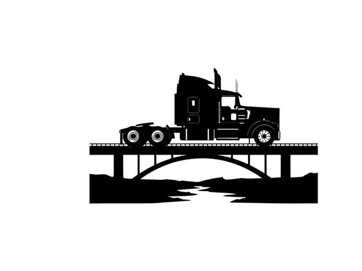 Silhouette of a semi truck on a bridge over a river