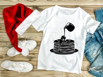 Black syrup pouring on pancake stack with clover design