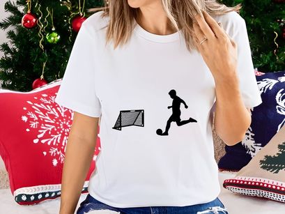 Silhouette of soccer player kicking ball towards goal