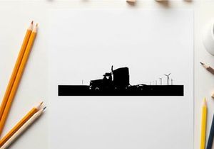 Silhouette of a semi truck driving on a road with wind turbines