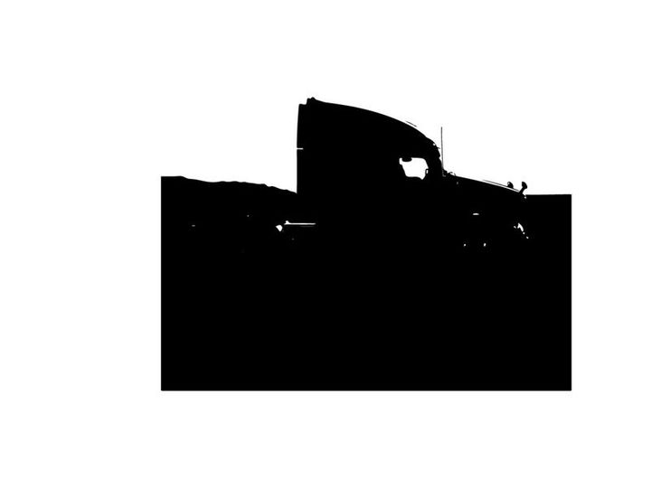 Silhouette of a semi truck driving on a road with mountains