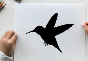 Silhouette of a hummingbird in flight against a white background