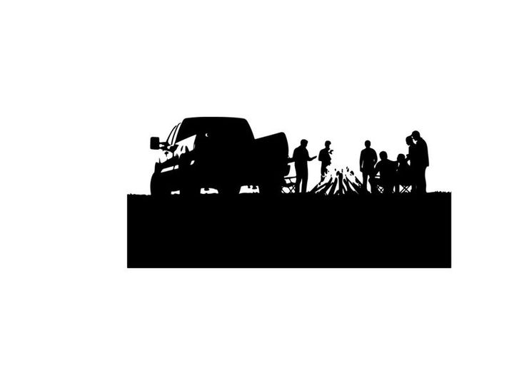 Silhouette of people gathered around campfire beside a truck