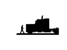 Silhouette of a man walking beside a large semi truck