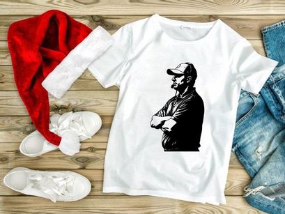 A man in a baseball cap standing with his arms crossed looking sideways