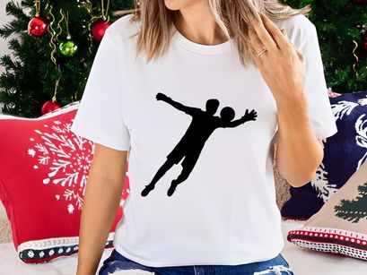 A silhouette of a person playing handball in mid air with outstretched arms and legs