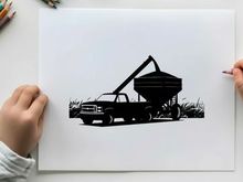 Silhouette of a pickup truck with grain auger in field