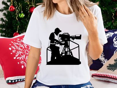 Silhouette of a cameraman operating a large video camera on a tripod stand