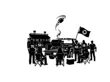 Silhouette of people gathered around a truck with a flag and building