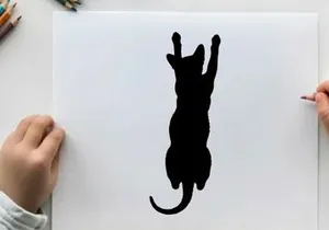 Silhouette of a cat jumping up with front paws raised high