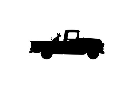 Silhouette of a dog sitting in the back of a vintage pickup truck