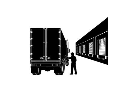 Silhouette of a man standing next to a truck at a warehouse dock