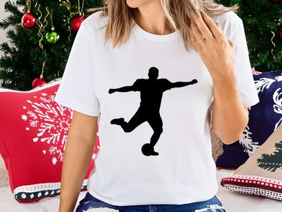 Silhouette of a soccer player kicking a ball in mid action