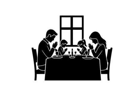Family in silhouette praying at dinner table together