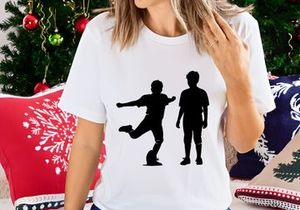 Two black silhouettes of boys playing soccer on a white background