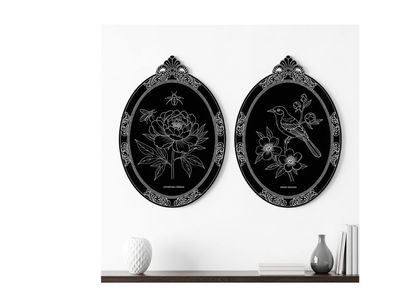 Silhouette artwork of two ornate oval frames on a shelf