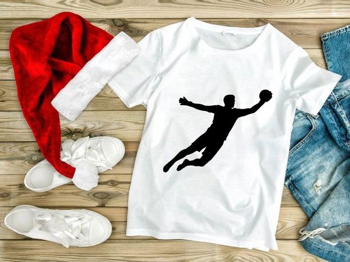 A silhouette of a person playing handball in mid air with outstretched arms and legs