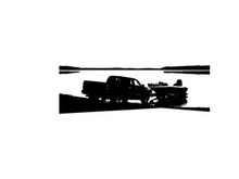 Silhouette of a pickup truck towing a boat on a road by the water