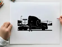 Silhouette of a man walking beside a large truck