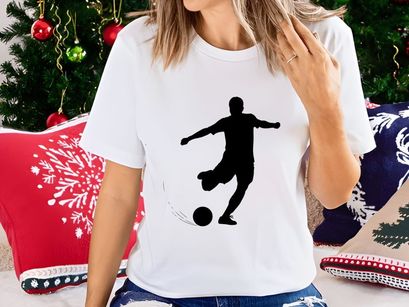 Silhouette of a soccer player kicking a ball in motion