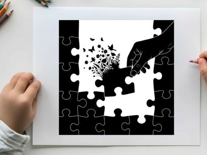 Silhouette of hand placing puzzle piece with butterflies and flowers emerging