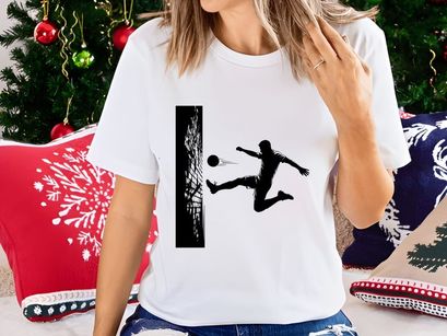 Soccer player kicking ball in mid air near goal net in black and white