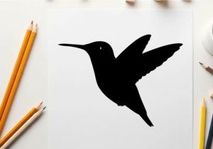 Silhouette of a hummingbird in flight against a white background