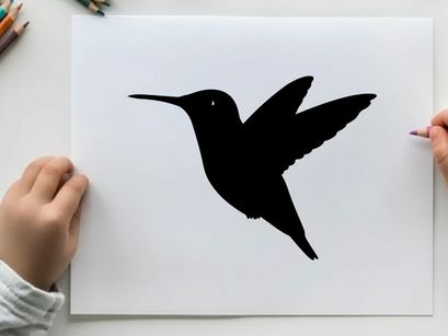 Silhouette of a hummingbird in flight against a white background