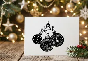 Black and white Christmas bauble ornaments hanging on a decorative scroll flourish.