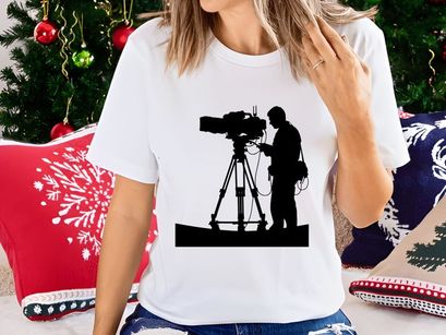 Silhouette of a cameraman operating a large video camera on a tripod stand