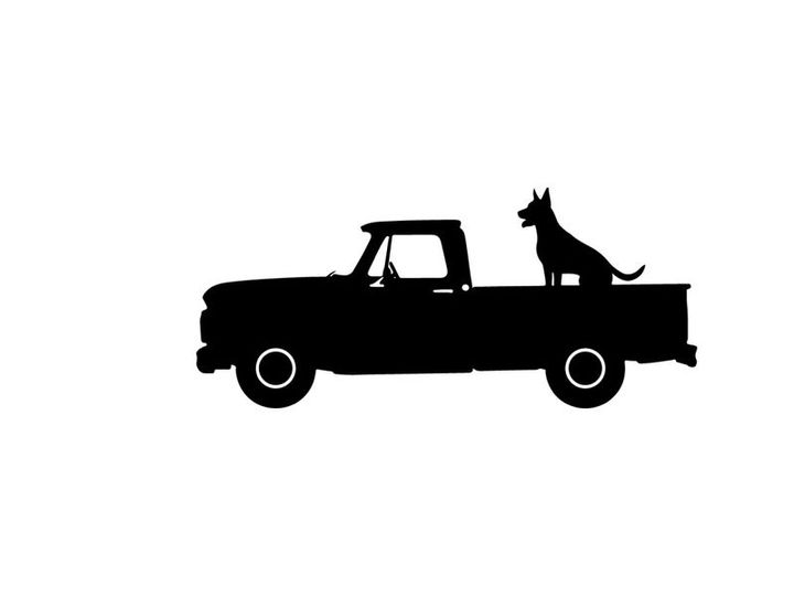 Silhouette of a dog sitting in the back of a pickup truck