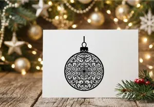Enfeite de bolinha de Natal preto e branco com design de padrão de filigrana floral intrincado.