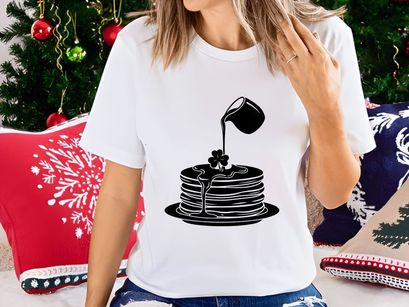 Black syrup pouring on pancake stack with clover design