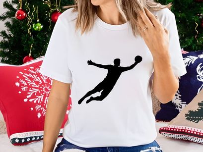 A silhouette of a person playing handball in mid air with outstretched arms and legs