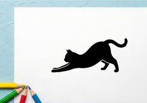 Silhouette of a playful black cat stretching on white background