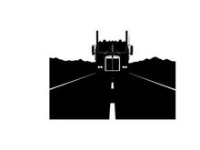 Silhouette of a semi truck driving on a deserted highway at night